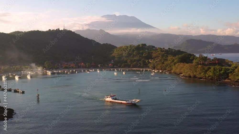 Cargo boat leaving the Padang Bai harbor in eastern Bali, Karangasem, with the majestic Agung volcano in the background in late afternoon in Indonesia. Cargo boat leaving the Padang Bai harbor in eastern Bali, Karangasem, with the majestic Agung volcano in the background in late afternoon in Indonesia.