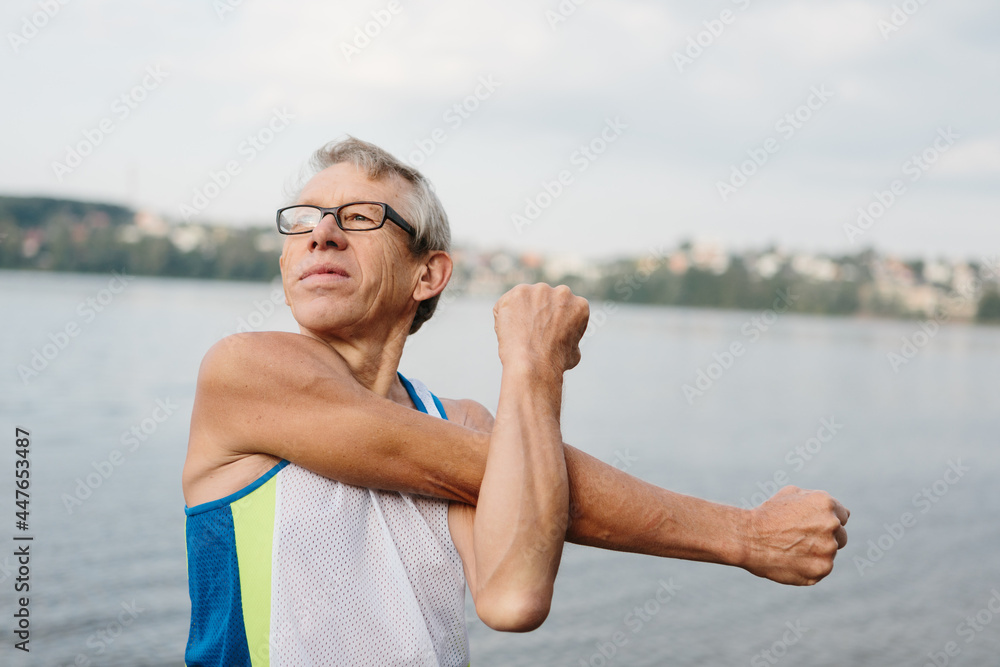 senior man is engaged in sports on the lake embankment