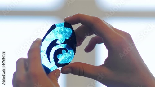 The artist looks at the light part of the stained glass. Artist's hands with part of stained glass sketch. Creation of a stained glass window, handmade.