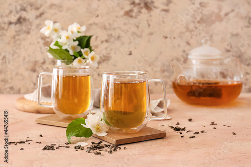 Cups of aromatic jasmine tea on color background