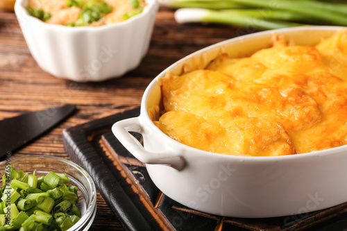 Baking dish with tasty potato casserole on wooden background, closeup