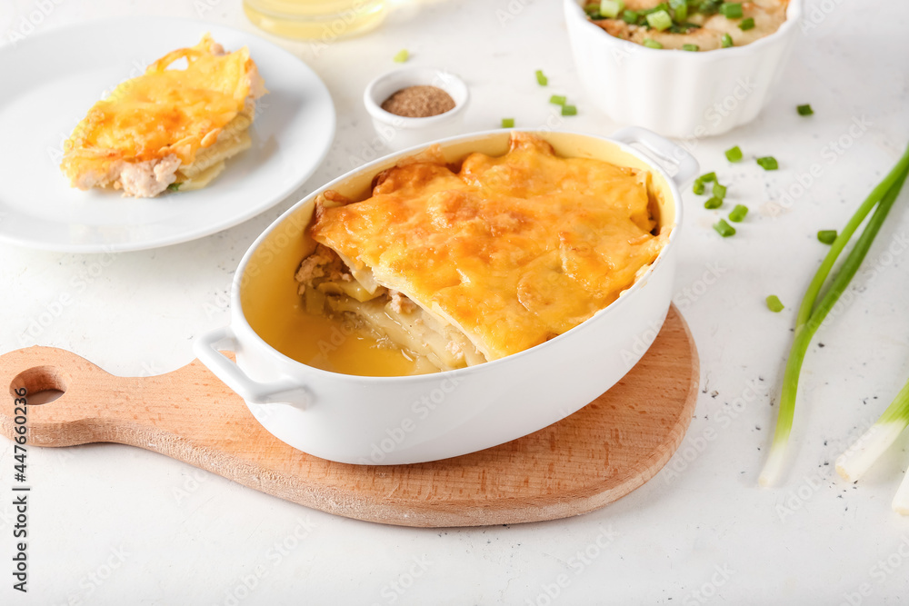 Baking dish with tasty potato casserole on light background Baking dish with tasty potato casserole on light background