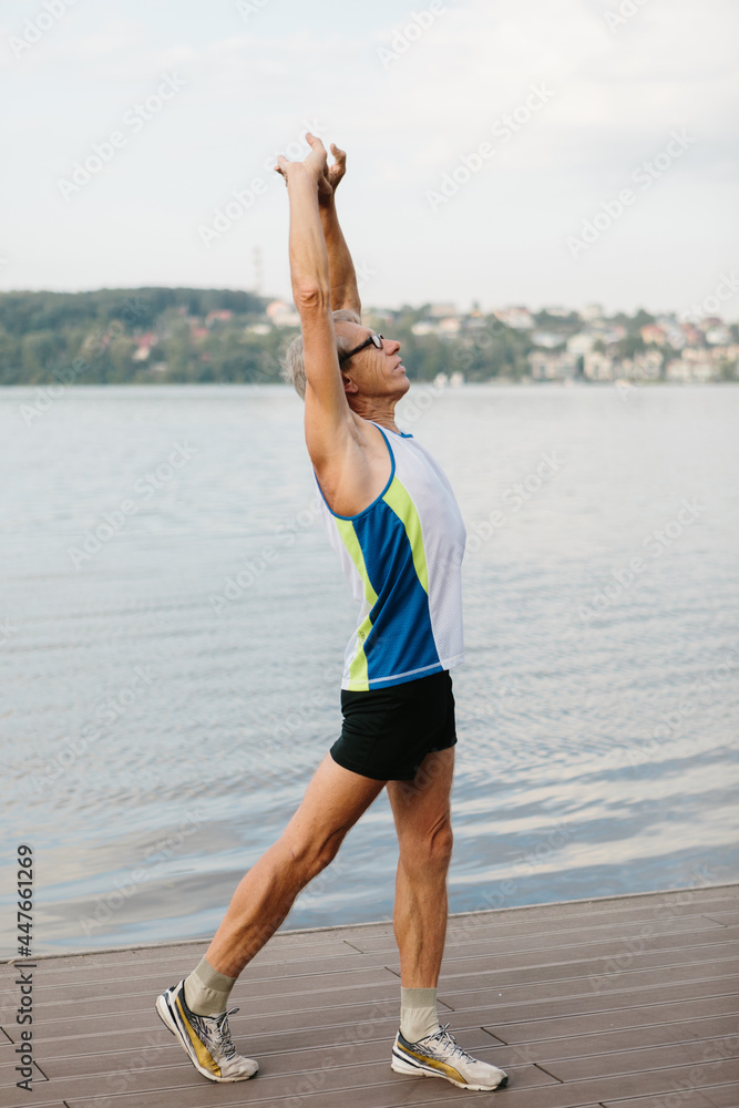 senior man is engaged in sports on the lake embankment senior man is engaged in sports on the lake embankment