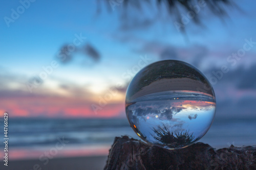beautiful cloud and golden sunset inside crystal ball placed on a timber beside the beach..beautiful nature in a crystal ball by the sea..Unique and creative travel and nature idea.. © Narong Niemhom