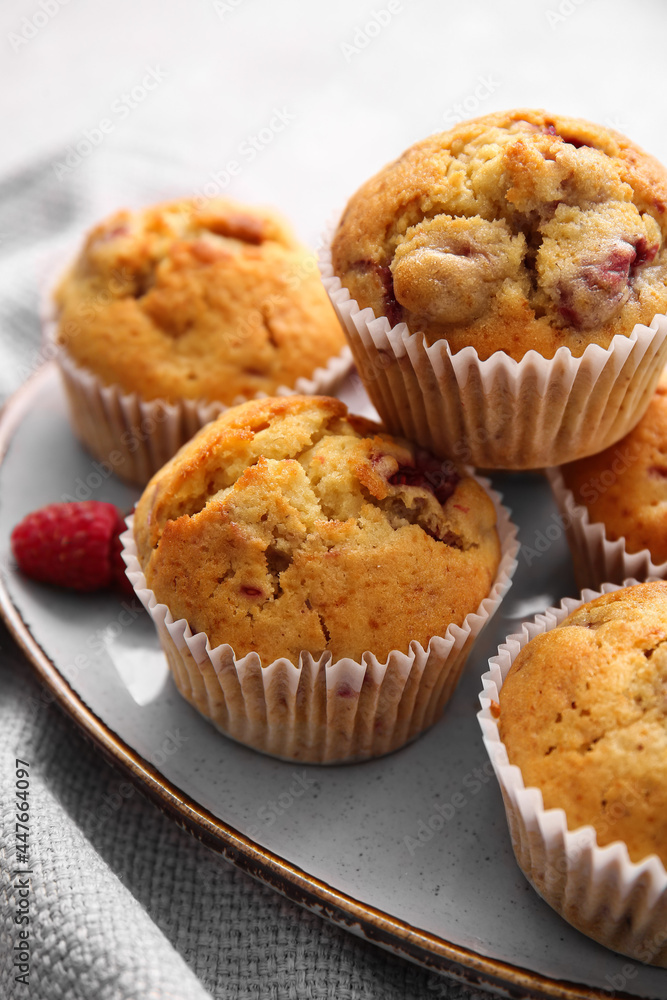 Plate with tasty raspberry muffins on light background, closeup Plate with tasty raspberry muffins on light background, closeup