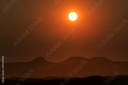 incredible view of setting sun above mountains in africa during sunset, red sky