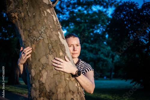 Fototapeta Naklejka Na Ścianę i Meble -  woman hand embracing a tree in the forest - nature loving, fight global warming, save planet earth