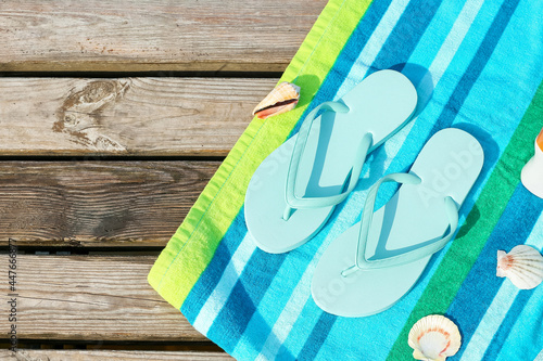 Stylish flip-flops and towel on wooden pier, closeup