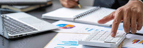 Fotografie A male accountant or a business man uses a laptop to calculate investment results