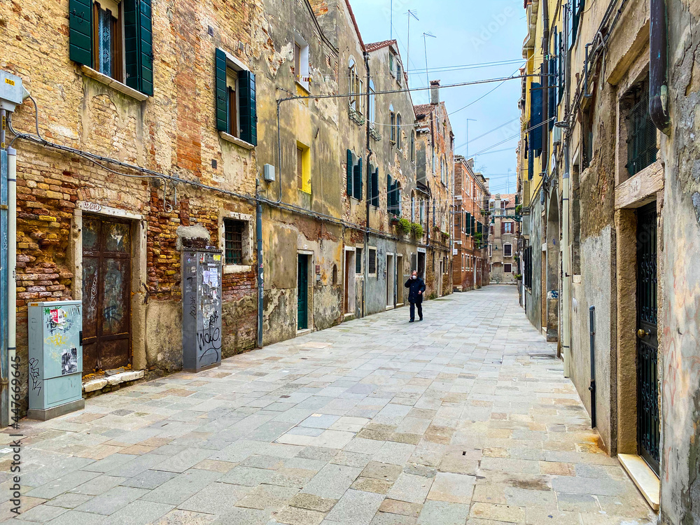Venice, Italy, February 19, 2021 - Unrecognizable people talking at phone with a protective mask and walking alone during the crisis COVID-19