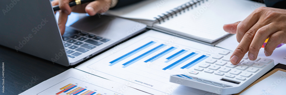Businessman discussing analysis charts or graphs on desk table and using a laptop computer. Close up male analysis and strategy concept. Businessman discussing analysis charts or graphs on desk table and using a laptop computer. Close up male analysis and strategy concept.