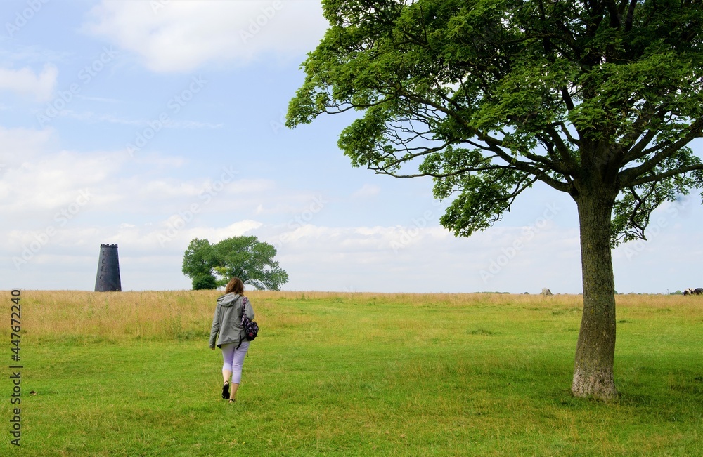 Woman approaching a black disused windmill, in Beverely, in the East Riding of Yorkshire, England. Woman approaching a black disused windmill, in Beverely, in the East Riding of Yorkshire, England.