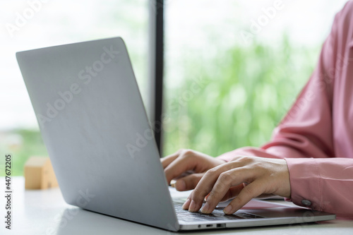 Businesswoman using laptop and analyzing financial data at office desk.