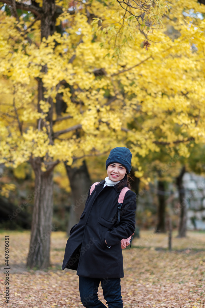 Happy woman enjoy at the park outdoor in Autumn season, Asian traveler in coat and hat against Yellow Ginkgo Leaves background Happy woman enjoy at the park outdoor in Autumn season, Asian traveler in coat and hat against Yellow Ginkgo Leaves background