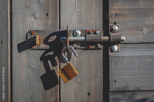 Brass padlock with bolt lock on wooden door. No key. photo