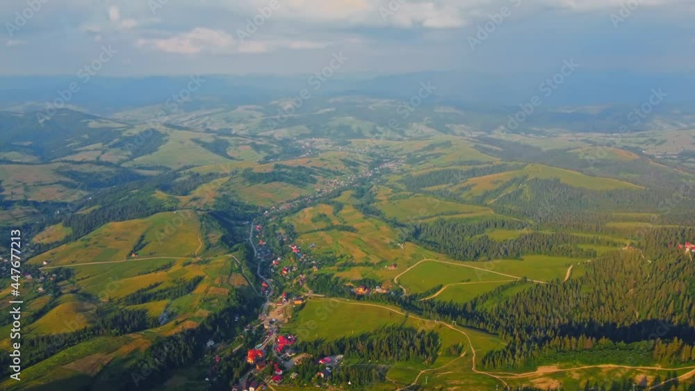 Aerial view of village in the Carpathian Mountains. Aerial drone shot flying over green treetops and nice houses. Summer countryside landscape in national park,nature background of mixed forest. Aerial view of village in the Carpathian Mountains. Aerial drone shot flying over green treetops and nice houses. Summer countryside landscape in national park,nature background of mixed forest.