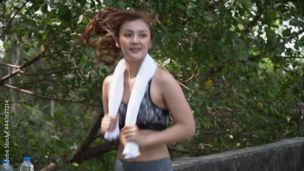 Young beautiful runner asian woman wearing sportswear with towel running or jog in park outdoors . fit jogger female exercise . sport training in morning . workout Young beautiful runner asian woman wearing sportswear with towel running or jog in park outdoors . fit jogger female exercise . sport training in morning . workout