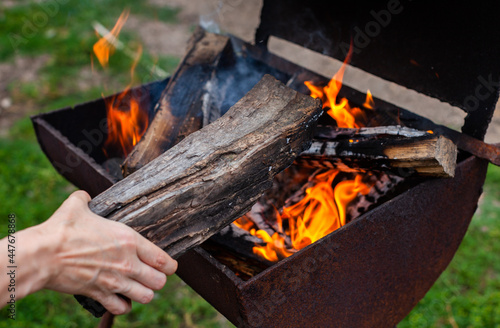 brazier with burning wood in which a man adds a log