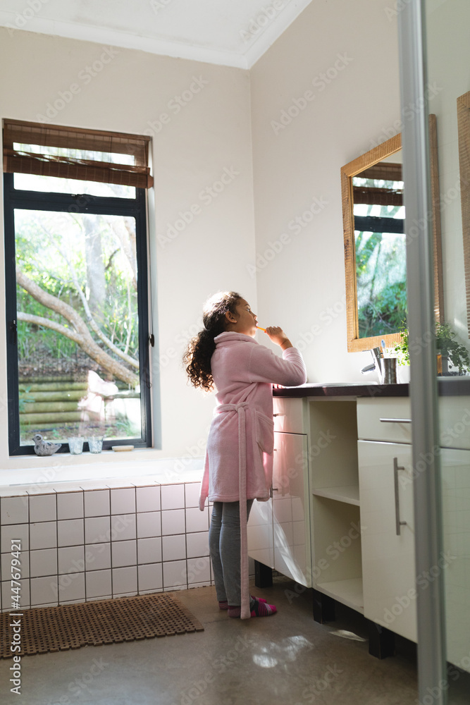 Mixed race girl looking at mirror and brushing teeth in bathroom Mixed race girl looking at mirror and brushing teeth in bathroom