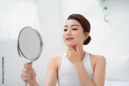 Pretty woman holding a mirror and smiling into the camera