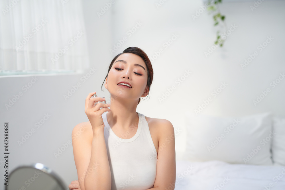 Woman sprays a perfume from a bottle on her neck. Woman sprays a perfume from a bottle on her neck.