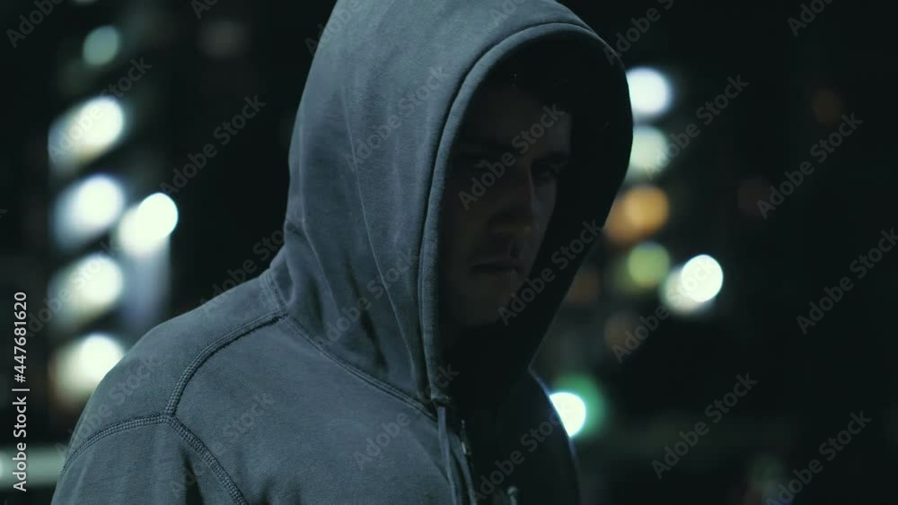 ugly mug - young hooded man looks at the camera in a threatening way - night ugly mug - young hooded man looks at the camera in a threatening way - night