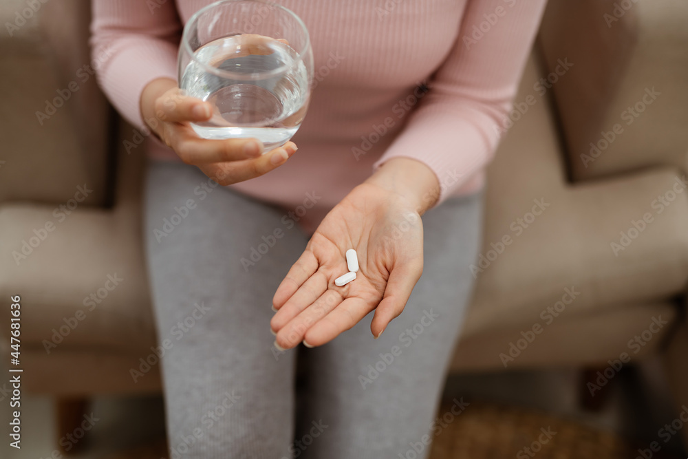 Woman holding a glass of water and pills, detail