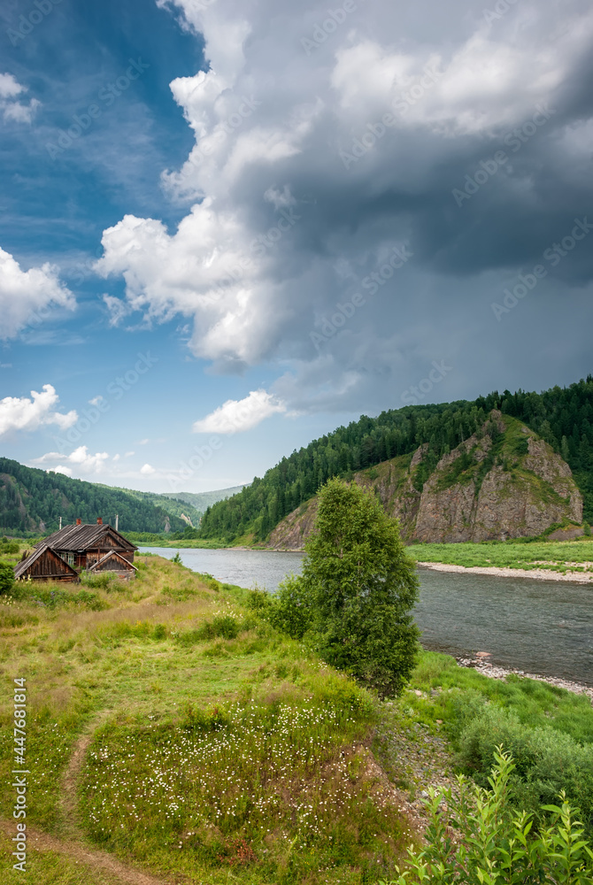 Fototapeta premium Landscape of Siberia. Kiya River, mountain banks and green forests in the Kemerovo region. Daytime landscape with blue skies and clouds.