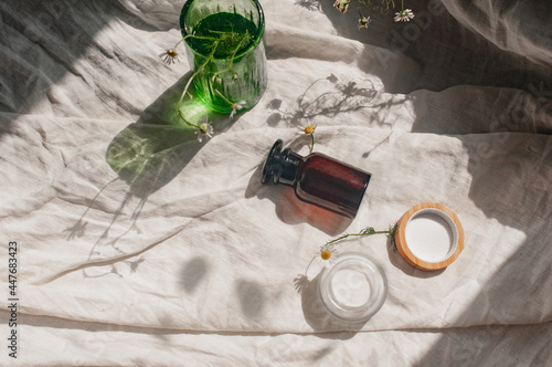 Sustainability concept cosmetic background brown glass green glass flowers camomille veil with product flat lay green natural beauty blog concept