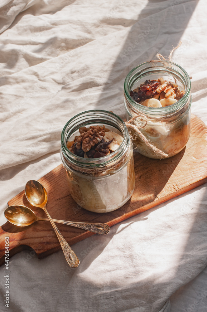 Fototapeta premium Delicious overnight oats with banana and walnuts minimalistic sunny shot walnuts baanaana sustainable concept linen background