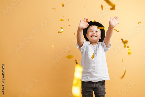 White boy with down syndrome in hat playing with confetti photo