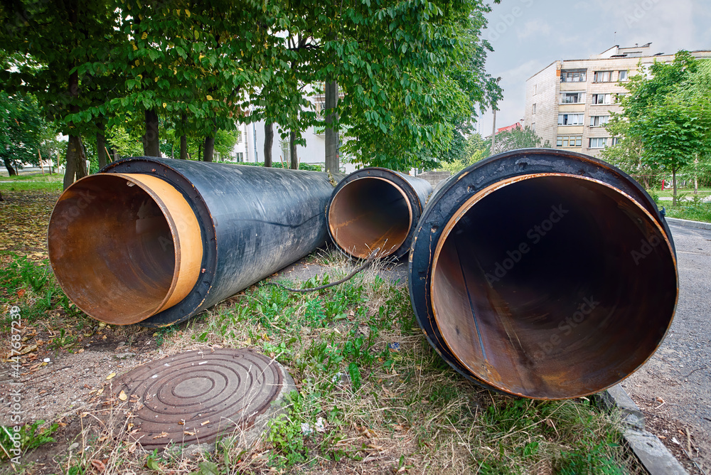 Water main replacement. Water pipes with insulation lie on the ground. Heating system pipelines - replacement and reconstruction. Stack of insulated pipes for pipeline, underground heat system.