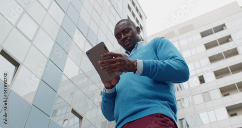 Low angle view of afro-american businessman using digital tablet outdoors
