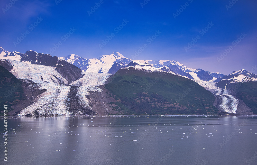 The glacier flows into the lake, which has bits of ice on the surface. Enjoy the view of the ice shelf from the cruise ship. Alaska, USA. July 2019.