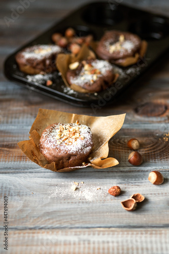 Chocolate muffins with hazelnuts. Fresh pastries on a wooden table. Chocolate homemade dessert in a baking dish