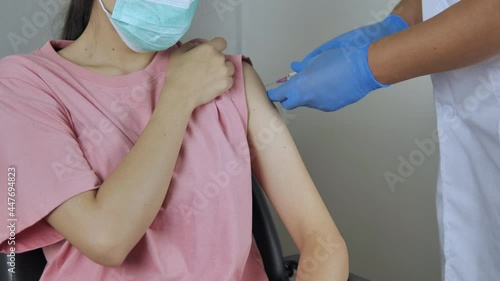 Doctor holds a syringe containing the vaccine to the woman's arm to prevent it. covid 19 virus