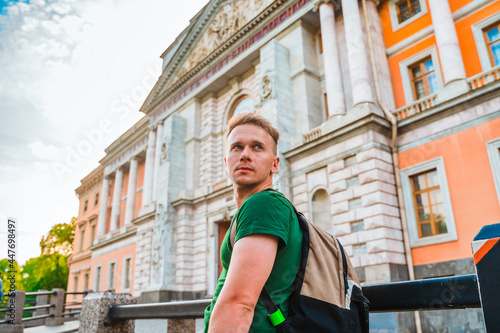 A young man in the center of St. Petersburg looks at the beautiful historical facade of the museum © KseniaJoyg