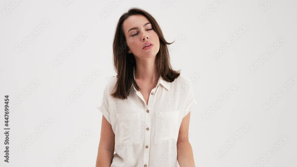 A bored woman wearing shirt is yawning standing in the studio isolated over white background A bored woman wearing shirt is yawning standing in the studio isolated over white background