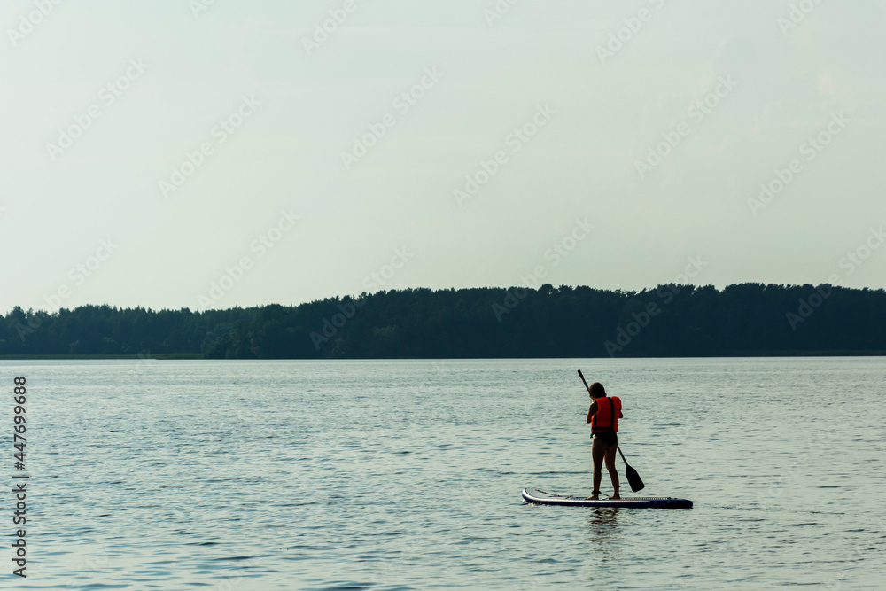 A young mother swims on a standing paddle board . SUP board. Water sports