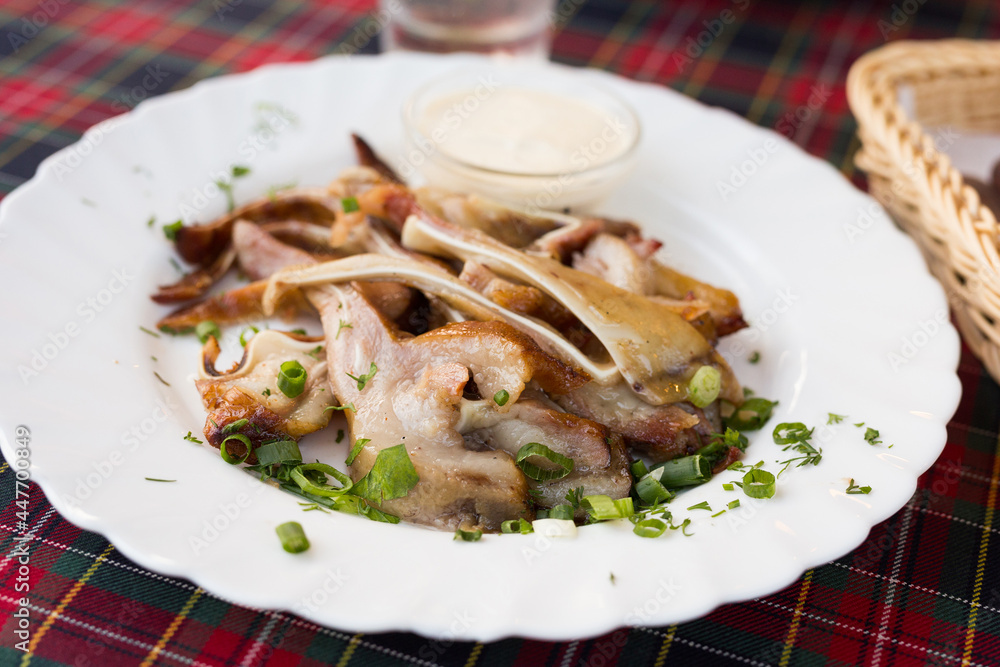 delicious smoked pork ears served with sour cream and herbs on a white plate in a restaurant delicious smoked pork ears served with sour cream and herbs on a white plate in a restaurant