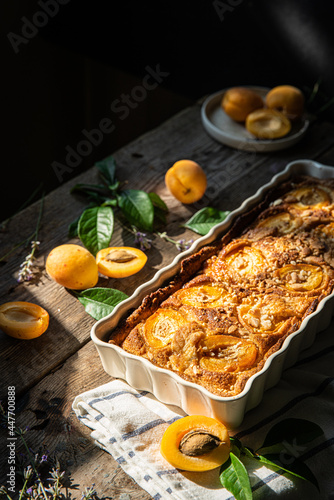 Apricot and frangipane tart in rectangular ceramic baking form on old wooden table.