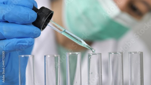 Doctor or scientist is using a test tube to drop a drop of liquid into a glass tube in the lab.