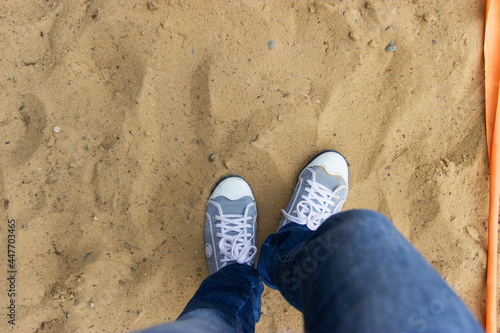 Womens legs jeans sneakers on sand