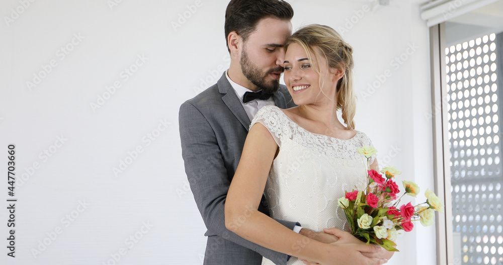 The lovers give flowers to the bride and kissed happy and couple love standing in wedding studio The lovers give flowers to the bride and kissed happy and couple love standing in wedding studio