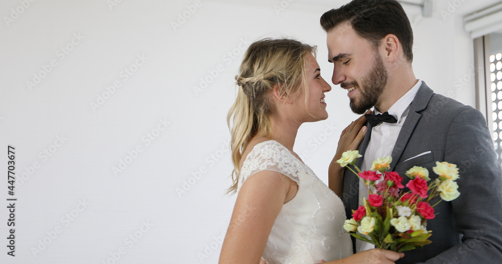 The lovers give flowers to the bride and kissed happy and couple love standing in wedding studio The lovers give flowers to the bride and kissed happy and couple love standing in wedding studio