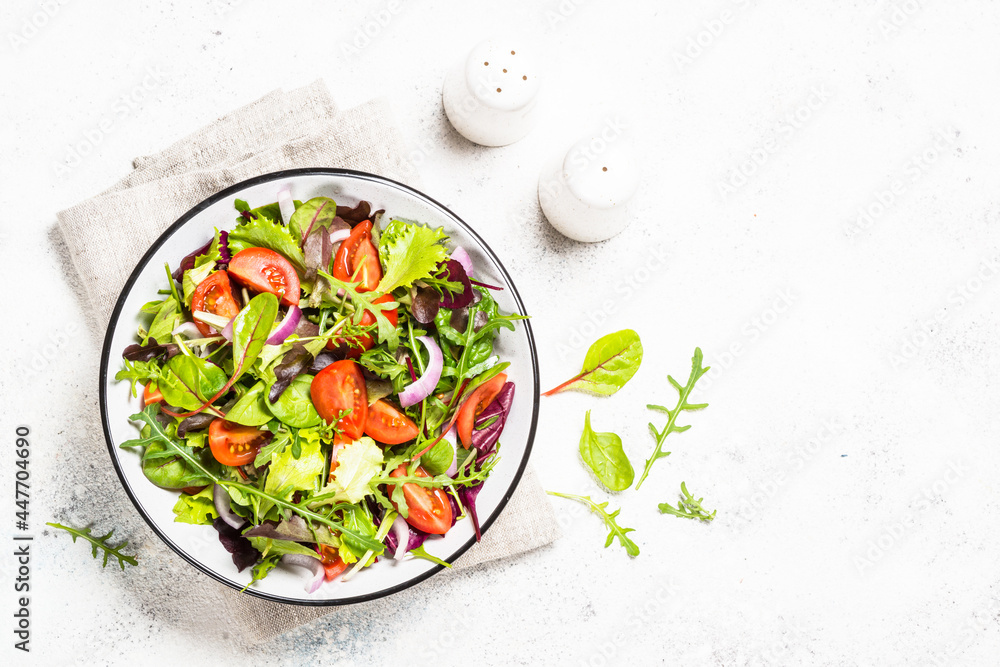 Green salad from fresh salad leaves and vegetables in white plate. Healthy vegan food. Top view image. Green salad from fresh salad leaves and vegetables in white plate. Healthy vegan food. Top view image.