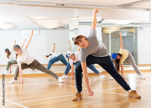 Focused teenage hip hop dancers doing dance workout during group class