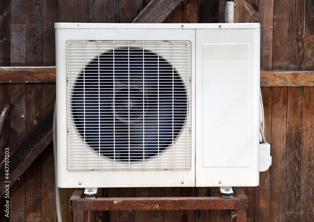The old air conditioner is installed on the old wooden facade of the building. The old air conditioner is installed on the old wooden facade of the building.