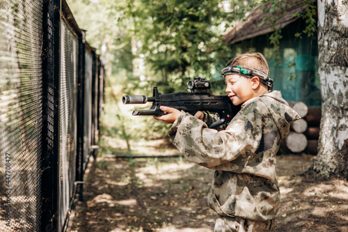 Boy looking into the optical sight a weapon. Children playing laser tag shooting game in outdoor. War simulation game