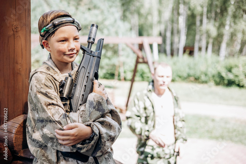 Boy with a weapon in his hand playing laser tag shooting game in outdoor. War simulation game